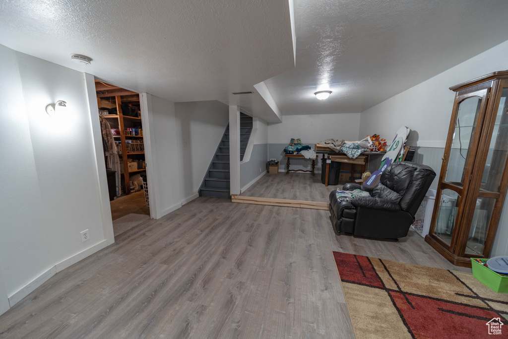 Finished below grade area with wood finished floors, stairs, and a textured ceiling