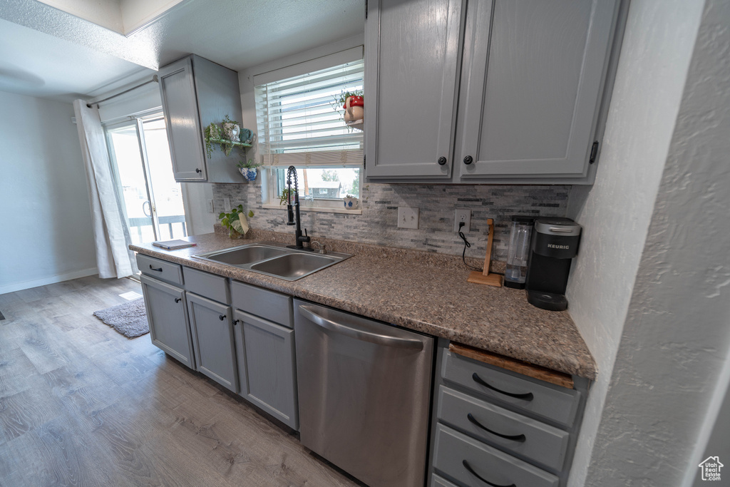 Kitchen with dishwasher, gray cabinets, backsplash, and light wood finished floors