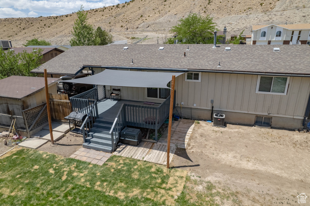 Back of property with a deck with mountain view and roof with shingles