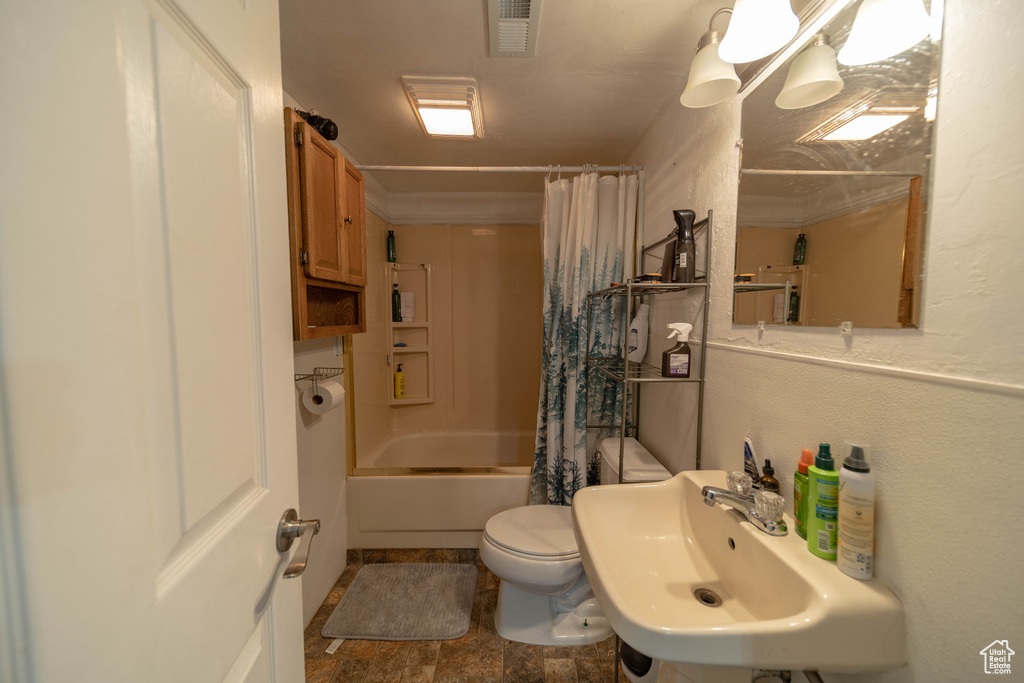 Full bath with shower / bath combination with curtain and stone finish floors