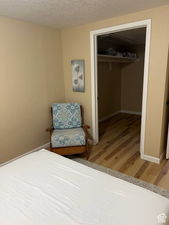 Bedroom featuring light wood-type flooring, a closet, and a textured ceiling
