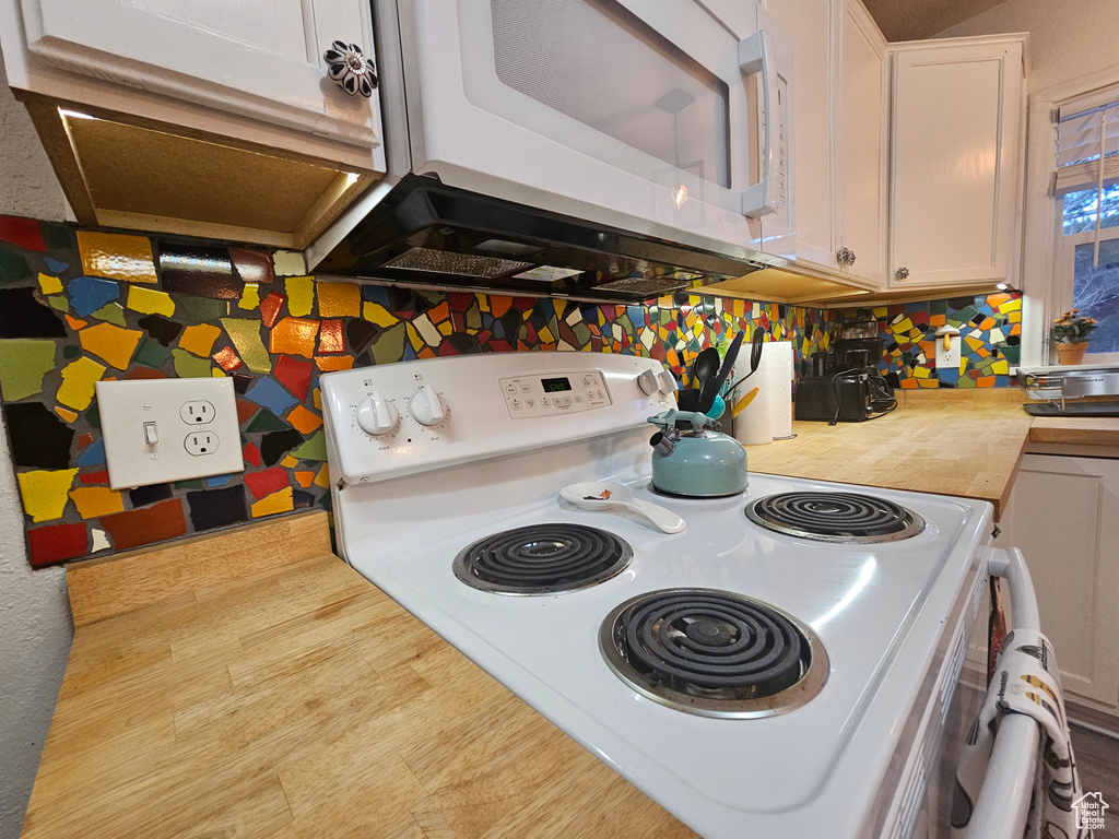 Kitchen featuring white appliances, light countertops, and white cabinets