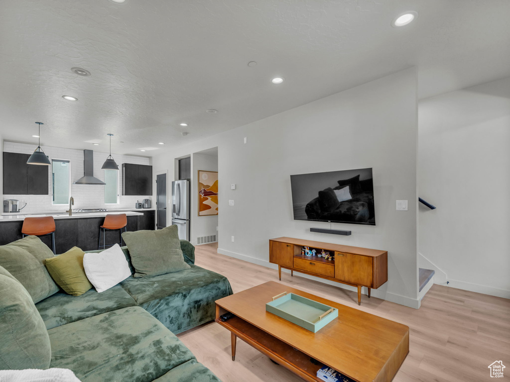 Living area with recessed lighting, light wood-style flooring, and stairs