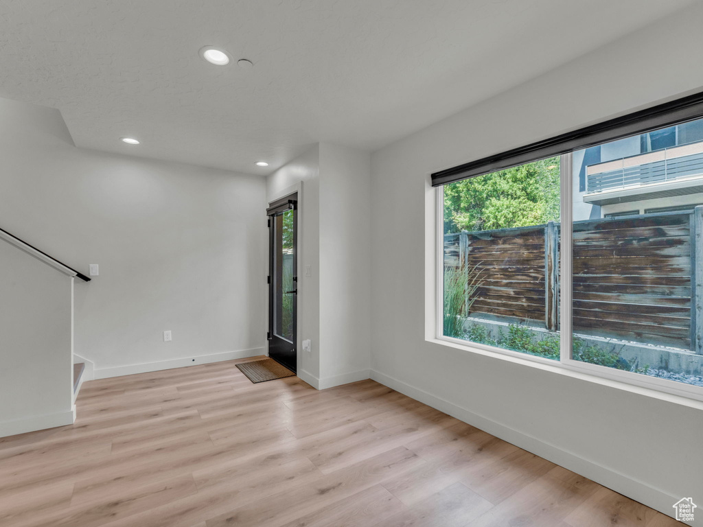 Empty room with healthy amount of natural light, recessed lighting, light wood-style floors, and stairs