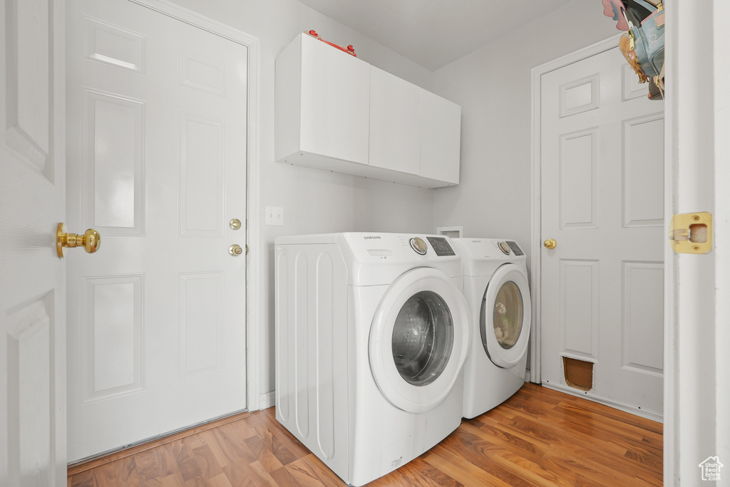 Washroom featuring cabinet space, washer and clothes dryer, and light wood-type flooring