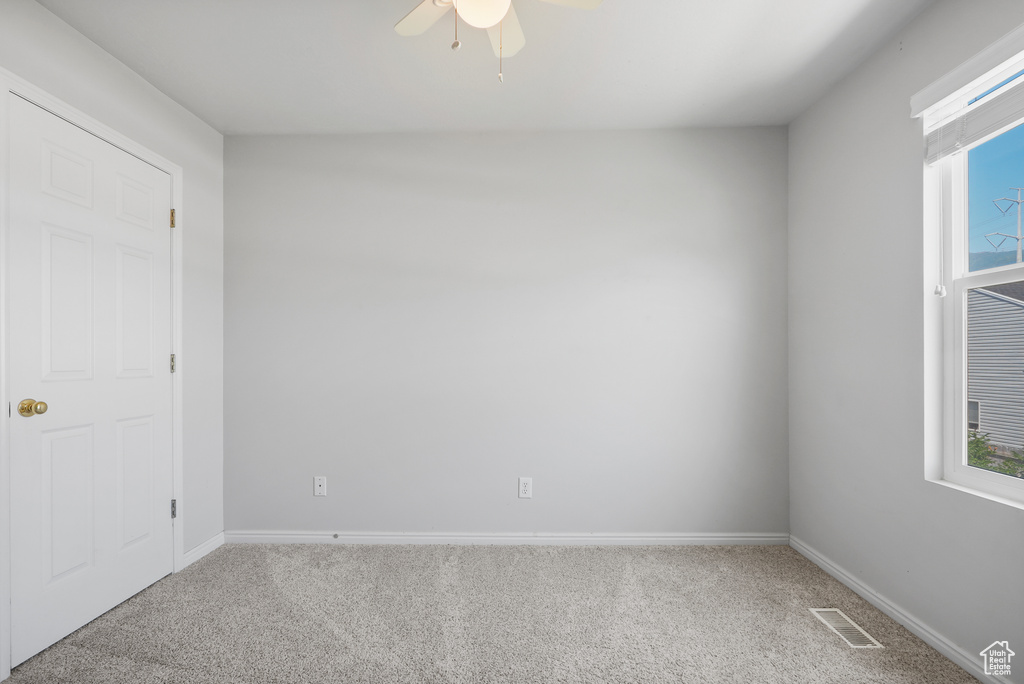 Unfurnished bedroom featuring carpet flooring, a ceiling fan, and multiple windows