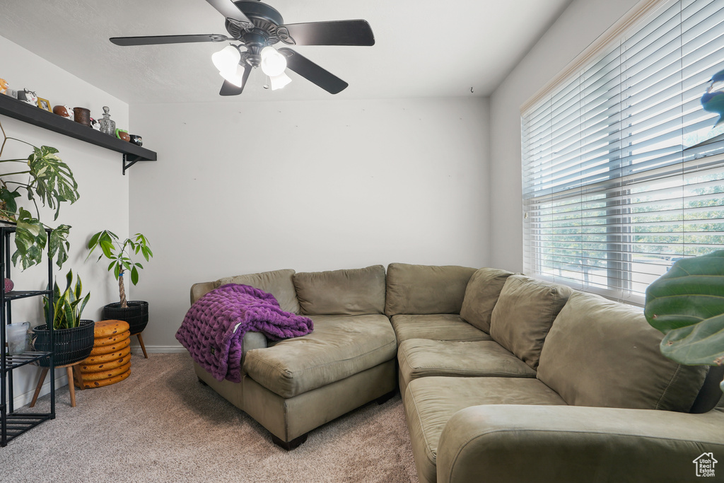 Carpeted living area with healthy amount of natural light and ceiling fan