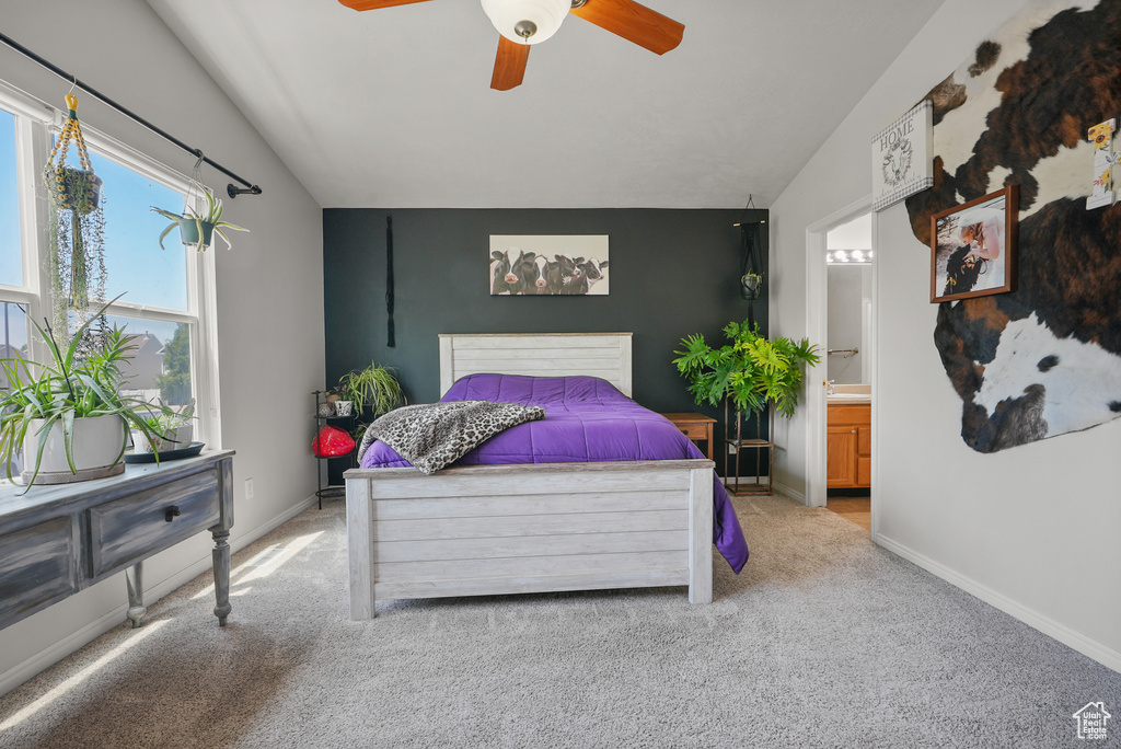 Bedroom featuring light colored carpet, lofted ceiling, ensuite bath, and ceiling fan