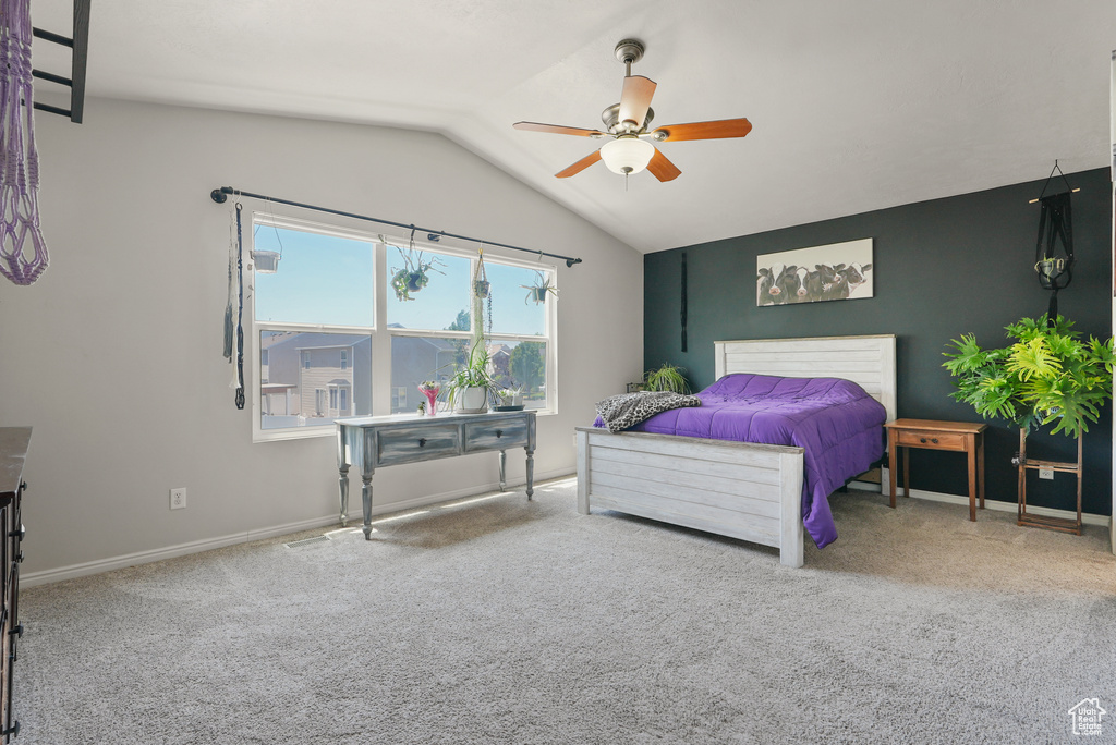 Carpeted bedroom featuring vaulted ceiling and a ceiling fan