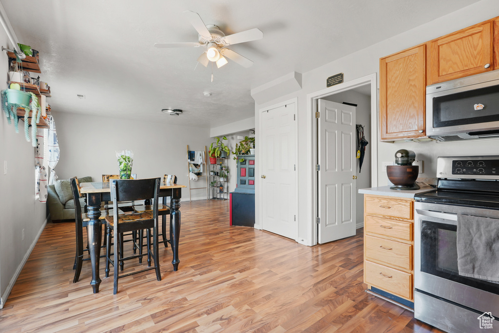 Kitchen with stainless steel appliances, light wood-style flooring, a ceiling fan, light brown cabinetry, and light countertops