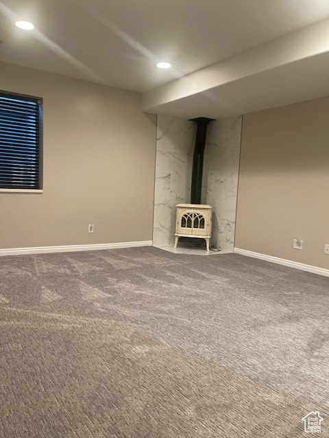 Unfurnished living room with a wood stove, carpet floors, and recessed lighting