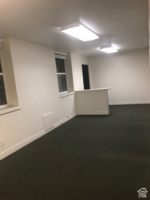 Spare room with baseboards and dark carpet