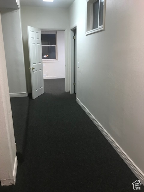 Hall with baseboards and dark carpet