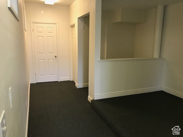 Hallway with dark carpet and baseboards