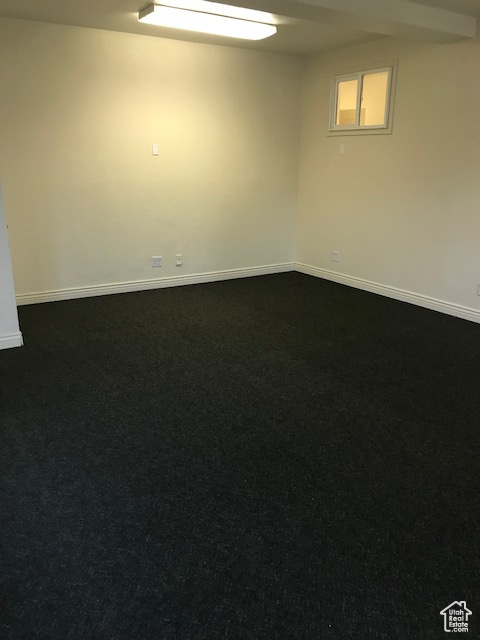 Spare room with dark carpet and baseboards