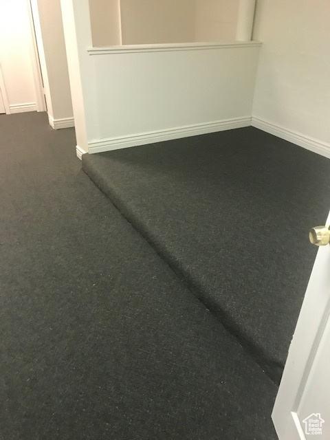 Unfurnished room with dark carpet and baseboards