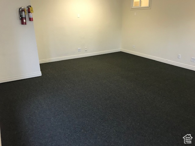 Unfurnished room featuring baseboards and dark colored carpet