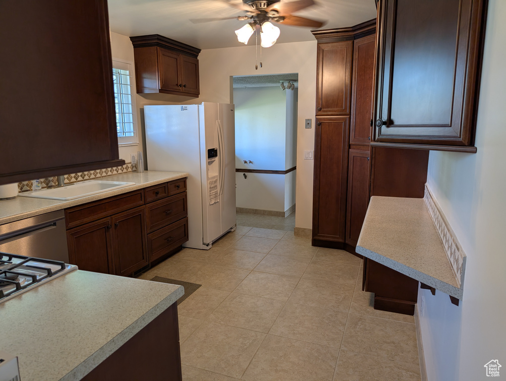 Kitchen featuring white refrigerator with ice dispenser, a ceiling fan, light countertops, stainless steel dishwasher, and light tile patterned floors