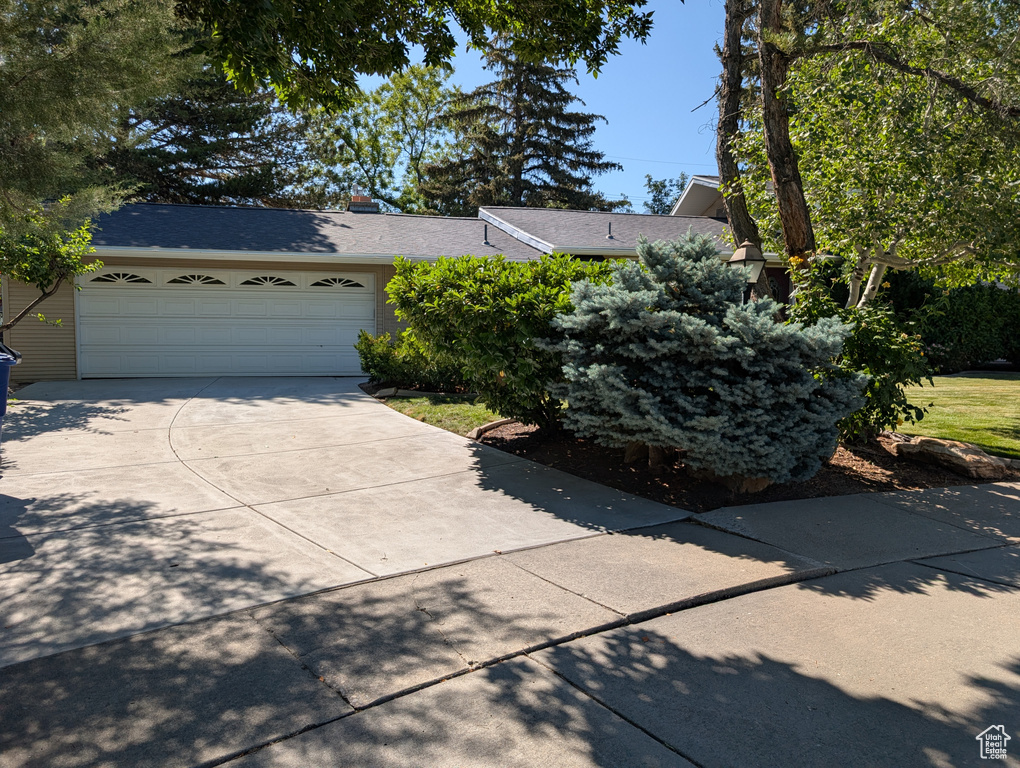 View of front of house featuring driveway, an attached garage, and roof with shingles