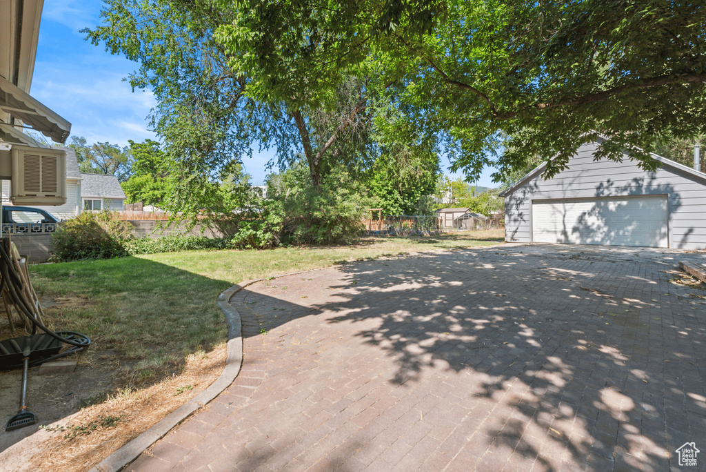 View of yard featuring an outdoor structure, a detached garage, and driveway