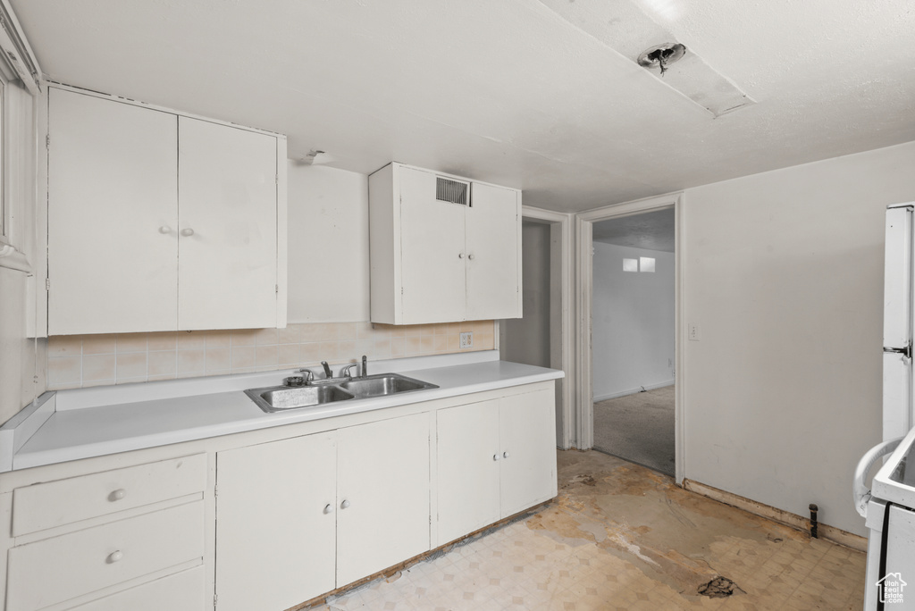 Kitchen featuring light countertops, white cabinets, range, and freestanding refrigerator