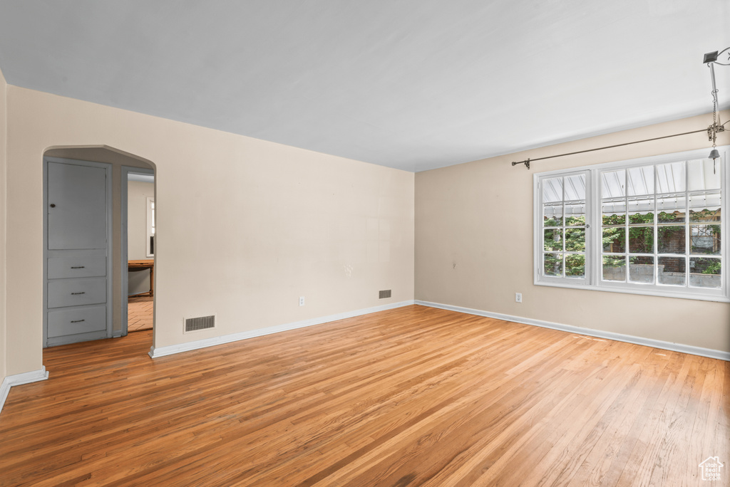 Spare room with light wood finished floors and arched walkways