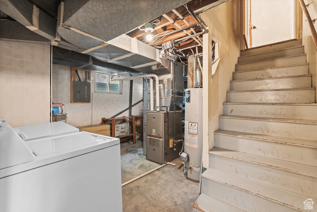 Below grade area featuring washer and dryer, electric panel, gas water heater, stairs, and heating unit