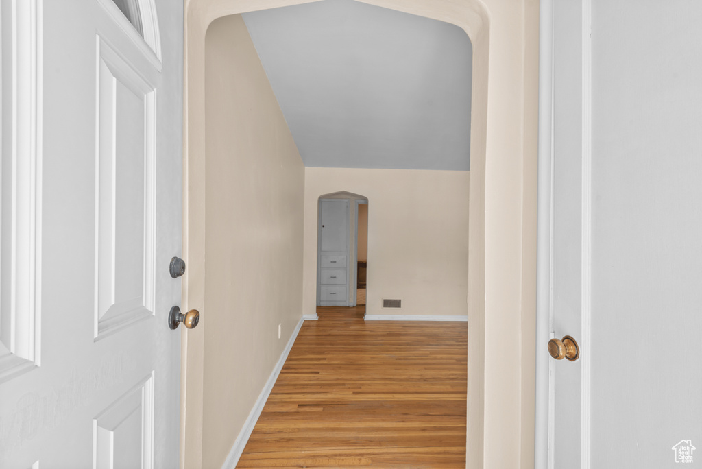Hallway featuring arched walkways and light wood-style floors