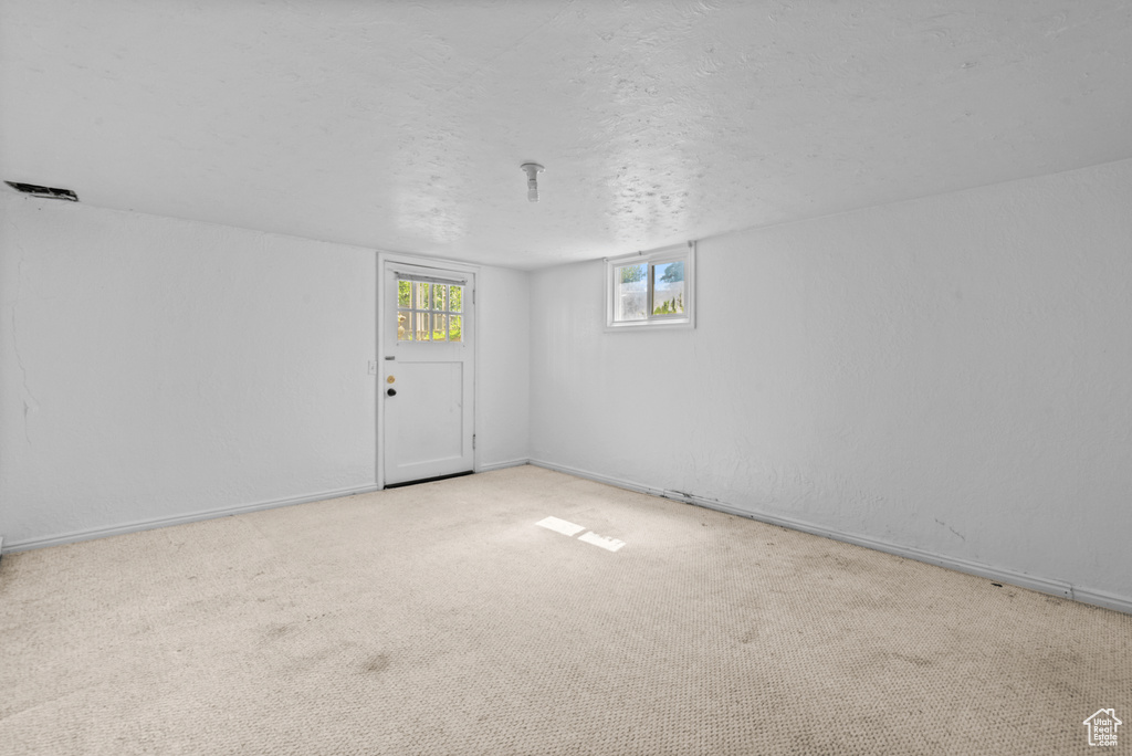 Carpeted spare room with a textured ceiling and baseboards