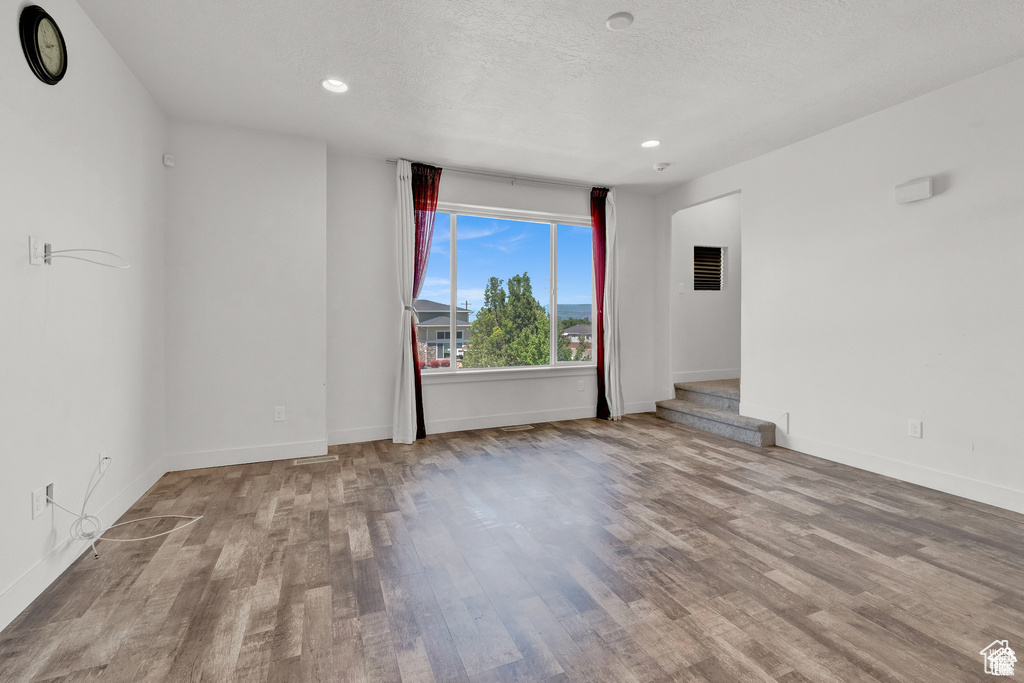 Spare room featuring wood finished floors, recessed lighting, and a textured ceiling