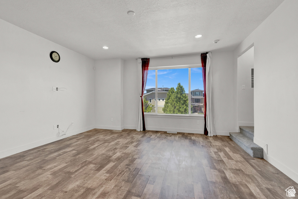 Empty room featuring wood finished floors, stairway, recessed lighting, and a textured ceiling