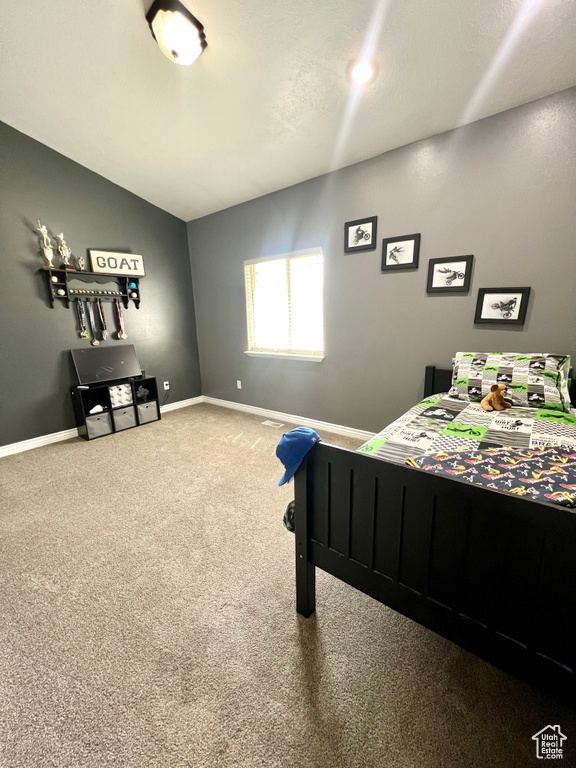Carpeted bedroom featuring lofted ceiling and baseboards