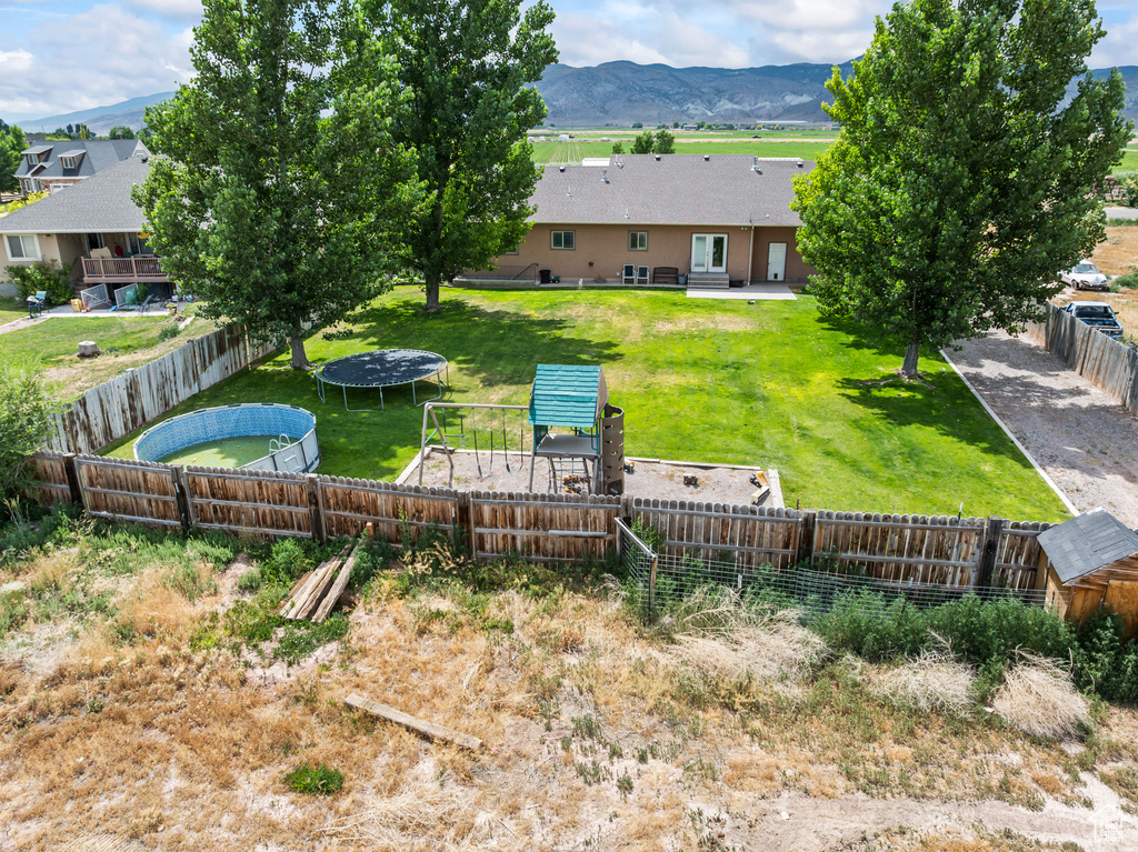 Fenced backyard with a trampoline and a mountain view