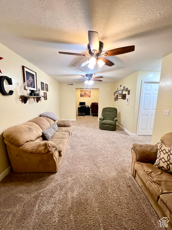 Carpeted living area featuring ceiling fan and a textured ceiling