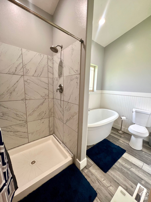 Bathroom with a wainscoted wall, a shower stall, a soaking tub, and wood finished floors