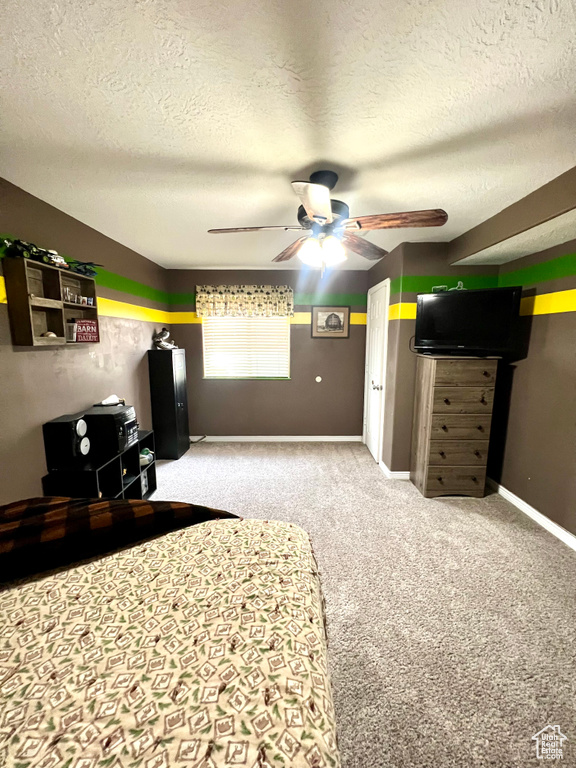Bedroom with a textured ceiling, light colored carpet, and a ceiling fan
