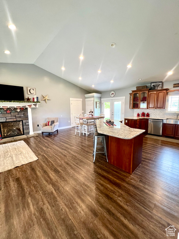 Kitchen featuring dishwasher, open floor plan, a kitchen island, lofted ceiling, and glass insert cabinets