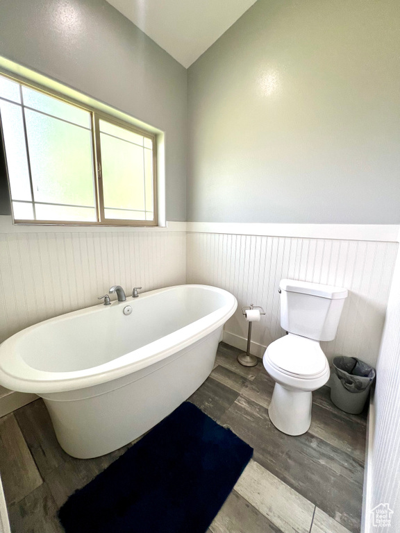Full bath featuring wainscoting, a soaking tub, and wood finished floors