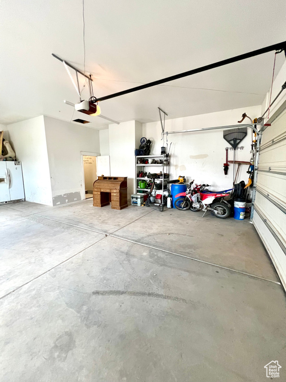 Garage featuring freestanding refrigerator and a garage door opener