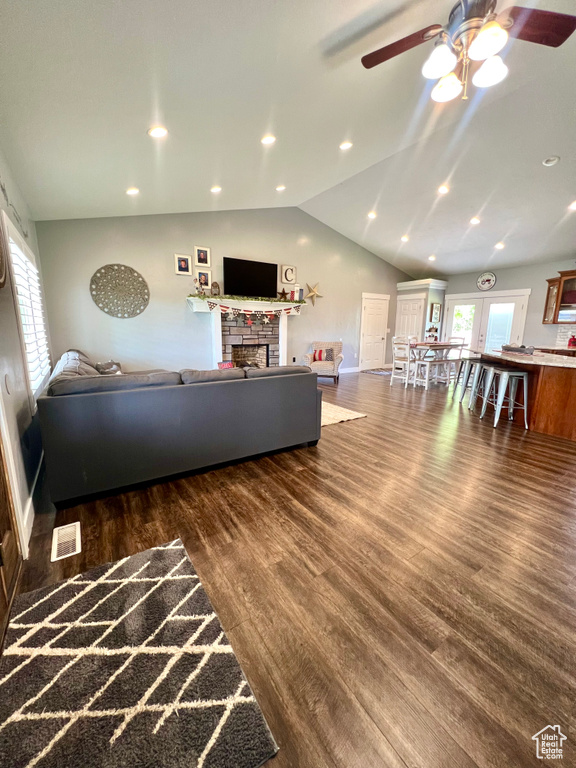 Living area with ceiling fan, vaulted ceiling, wood finished floors, a stone fireplace, and recessed lighting