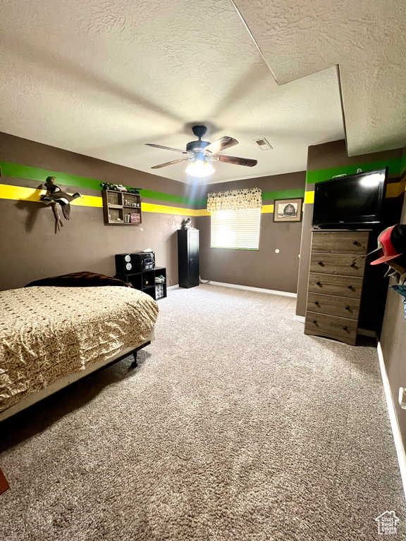 Bedroom featuring a textured ceiling, carpet flooring, and ceiling fan