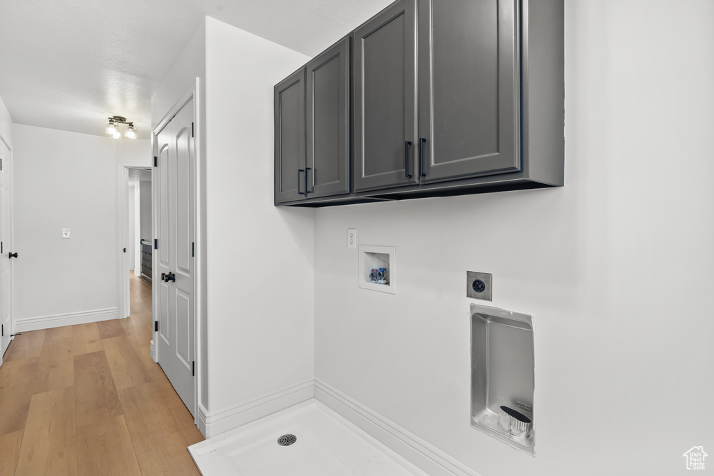 Laundry room with hookup for an electric dryer, washer hookup, cabinet space, and light wood-style flooring