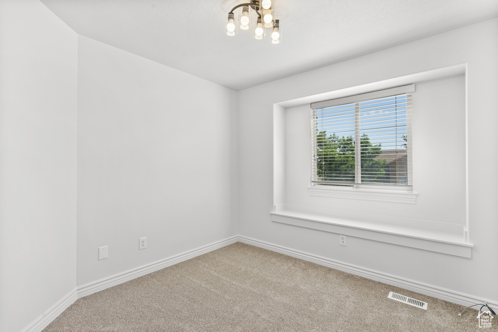Unfurnished room featuring carpet floors and a chandelier