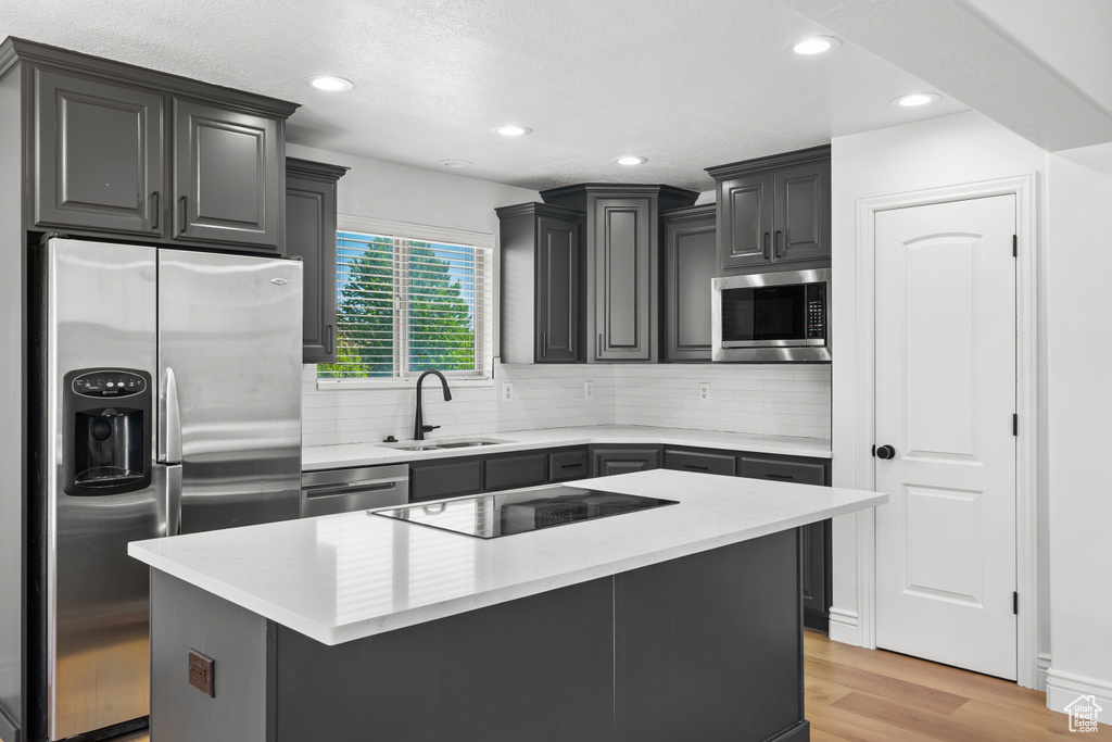 Kitchen featuring stainless steel appliances, tasteful backsplash, light wood-type flooring, recessed lighting, and a center island