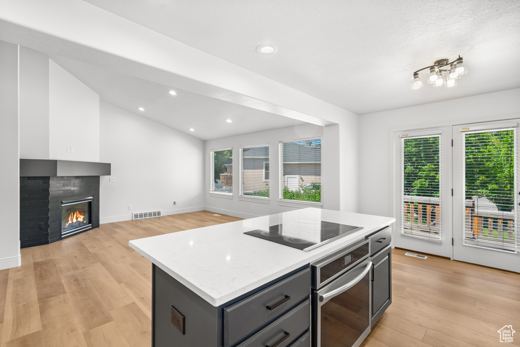 Kitchen with oven, black electric stovetop, light wood-type flooring, plenty of natural light, and recessed lighting