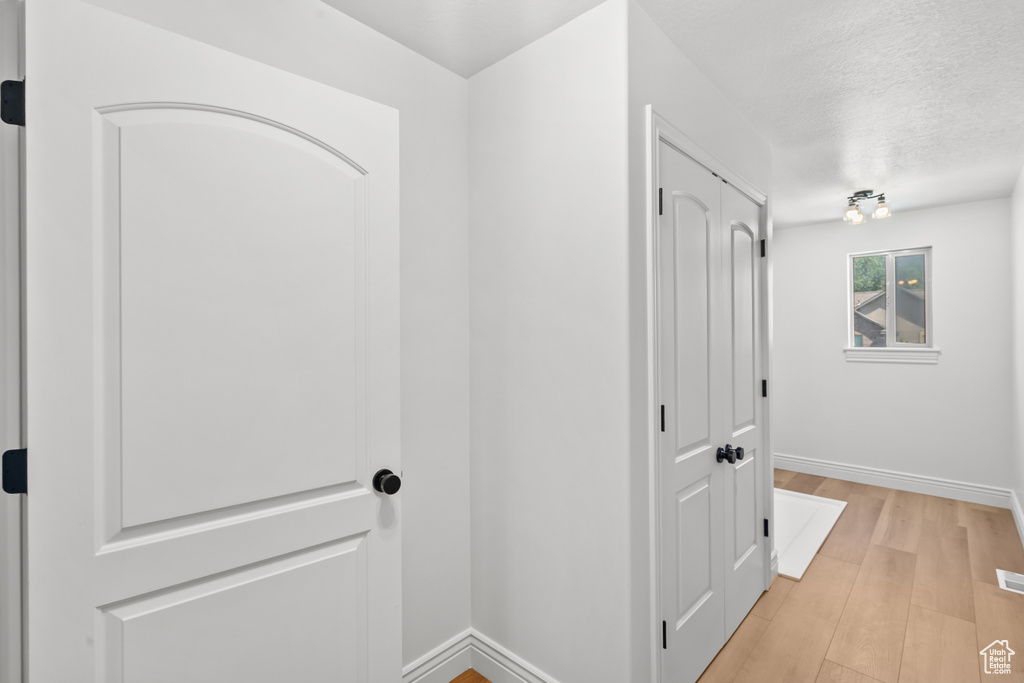 Hall featuring light wood-type flooring and a textured ceiling