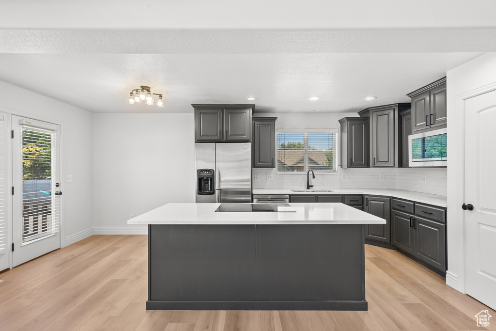 Kitchen with stainless steel fridge, light wood-style flooring, light countertops, and recessed lighting
