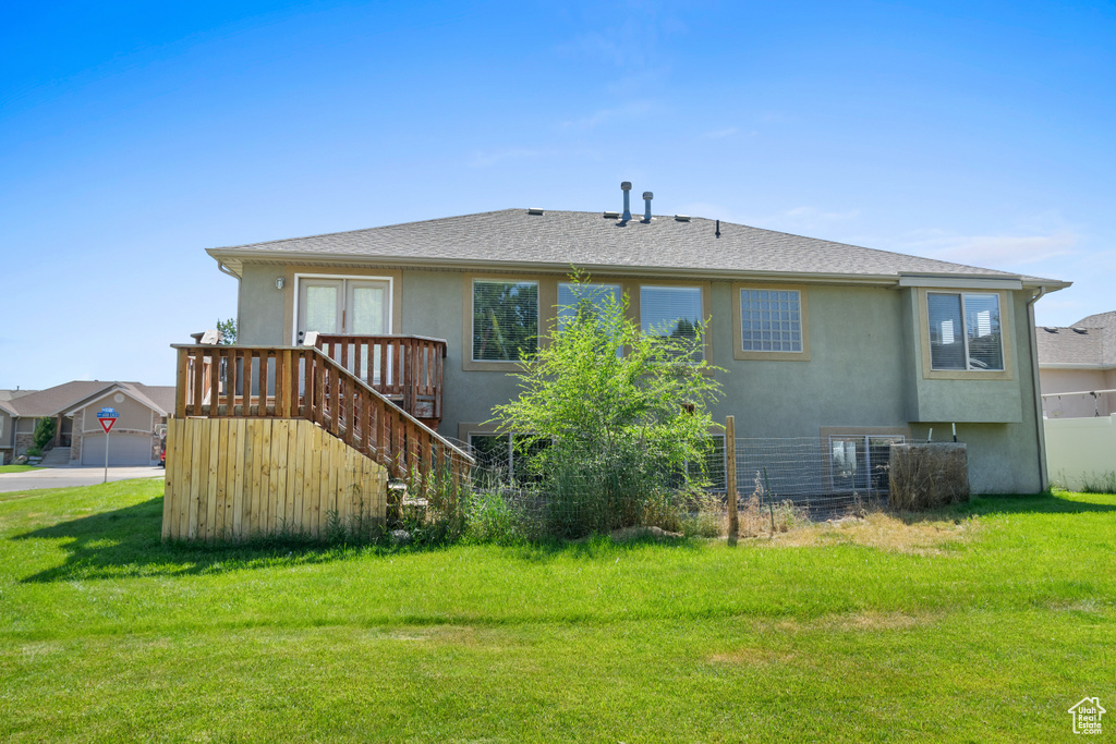 Rear view of house featuring stucco siding, a yard, stairway, and a shingled roof