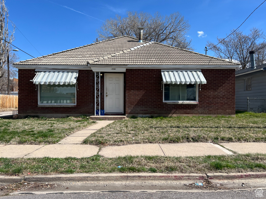 Bungalow-style home featuring brick siding and a tiled roof