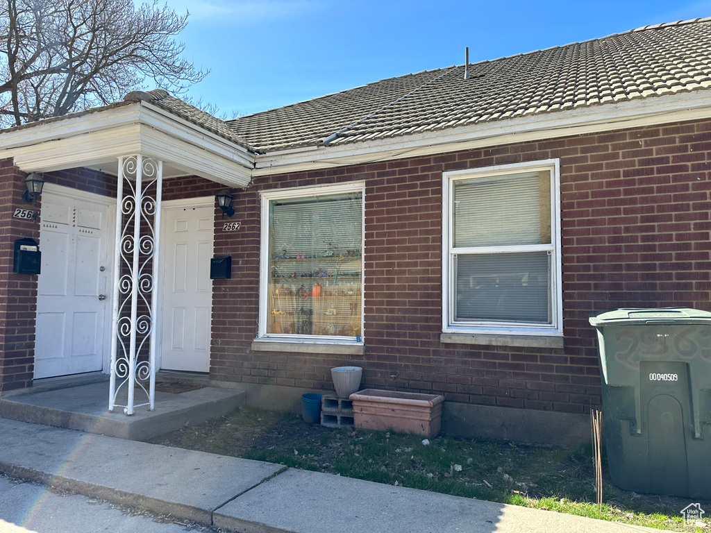 View of exterior entry with brick siding and a tile roof